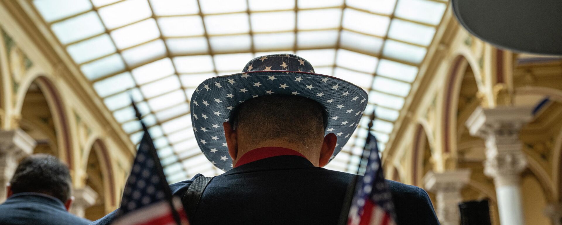 Мужчина в шляпе с американским флагом виден в здании Капитолия - Sputnik Молдова, 1920, 20.08.2022