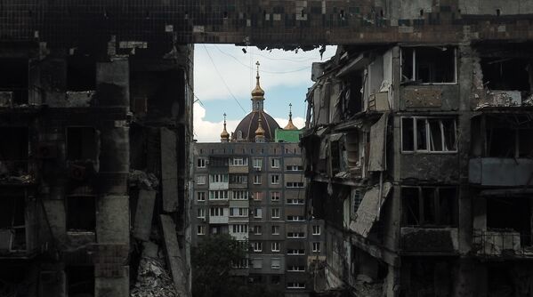 Вид на Покровский храм через разрушенный многоквартирный дом в Мариуполе - Sputnik Молдова