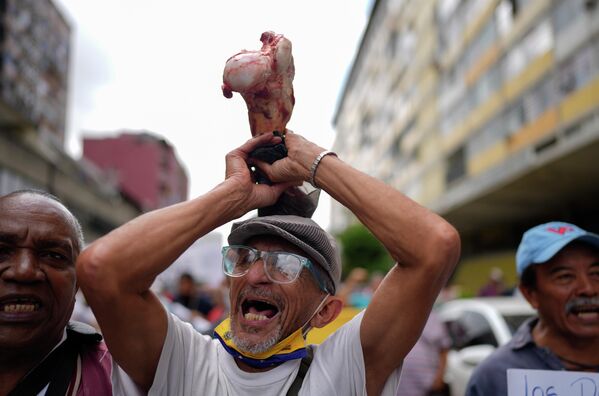Мужчина держит кость в знак протеста против голода во время демонстрации активистов и вышедших на пенсию государственных служащих, в том числе учителей, требующих повышения заработной платы в Каракасе, Венесуэла. - Sputnik Молдова