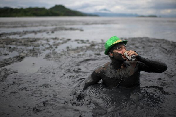 Мужчина пьет пиво, принимая участие в грязевом карнавале &quot;Блок да Лама&quot; в Парати, штат Рио-де-Жанейро, Бразилия. - Sputnik Молдова