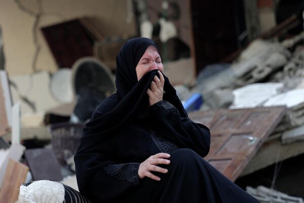 O femeie palestiniană reacționează în timp ce stă în mijlocul dărâmurilor casei ei, distruse în timpul atacurilor aeriene israeliene de peste noapte în orașul Gaza, pe 7 august 2022. - Sputnik Moldova-România