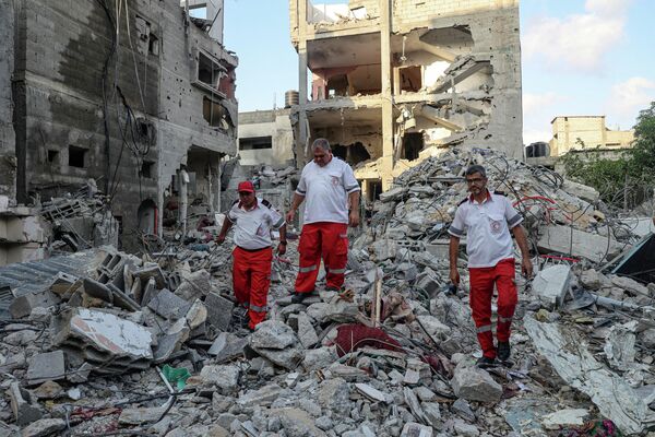 Salvatorii merg printre dărâmăturile unei clădiri, în urma atacurilor aeriene israeliene de la Rafah, în sudul Fâșiei Gaza, pe 7 august 2022. - Sputnik Moldova-România