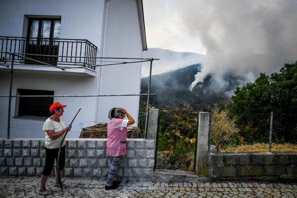 Oamenii urmăresc răspândirea unui incendiu de pădure în satul Sameiro, lângă orașul Manteigas, pe 10 august 2022. - Un incendiu de vegetație izbucnit sâmbătă a făcut ravagii în parcul natural Serra da Estrela din centrul Portugaliei. - Sputnik Moldova-România