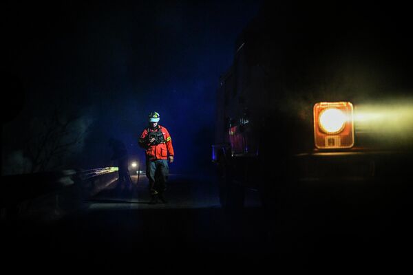 Un pompier merge pe șosea lângă o camionetă de pompieri în timpul unui incendiu din Manteigas, centrul Portugaliei, pe 10 august 2022. - Un incendiu care a izbucnit pe 6 august a făcut ravagii în parcul natural Serra da Estrela. - Sputnik Moldova-România