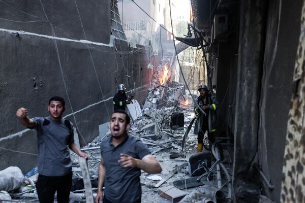 Спасатели и пожарные тушат пожар среди разрушений после израильского авиаудара по городу Газа - Sputnik Молдова
