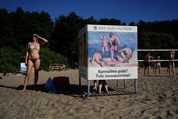 Женщина стоит рядом с кабинкой для переодевания на пляже Пирита в Таллине, Эстония - Sputnik Молдова