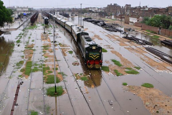 Поезд движется по затопленным железнодорожным путям после сильных муссонных дождей в Хайдарабаде  - Sputnik Молдова