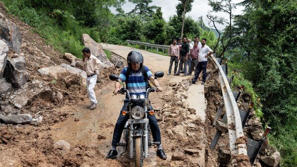 Мотоциклист пытается проехать через перекрытую оползнем дорогу в Дхарамсале, штат Химачал-Прадеш, Индия - Sputnik Moldova-România