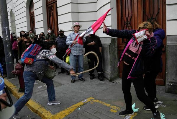 Сторонник президента Перу Педро Кастильо наносит удар защитнику возле суда в Лиме. - Sputnik Молдова