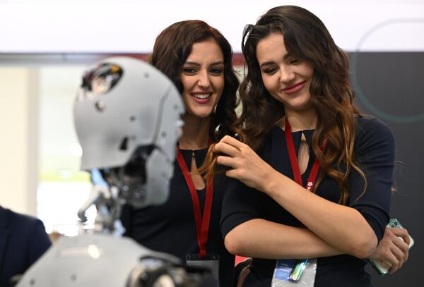 Câteva participante la Forumul Economic de Est din Vladivostok  examinează robotul-promoter de serviciu „Alex”. - Sputnik Moldova-România