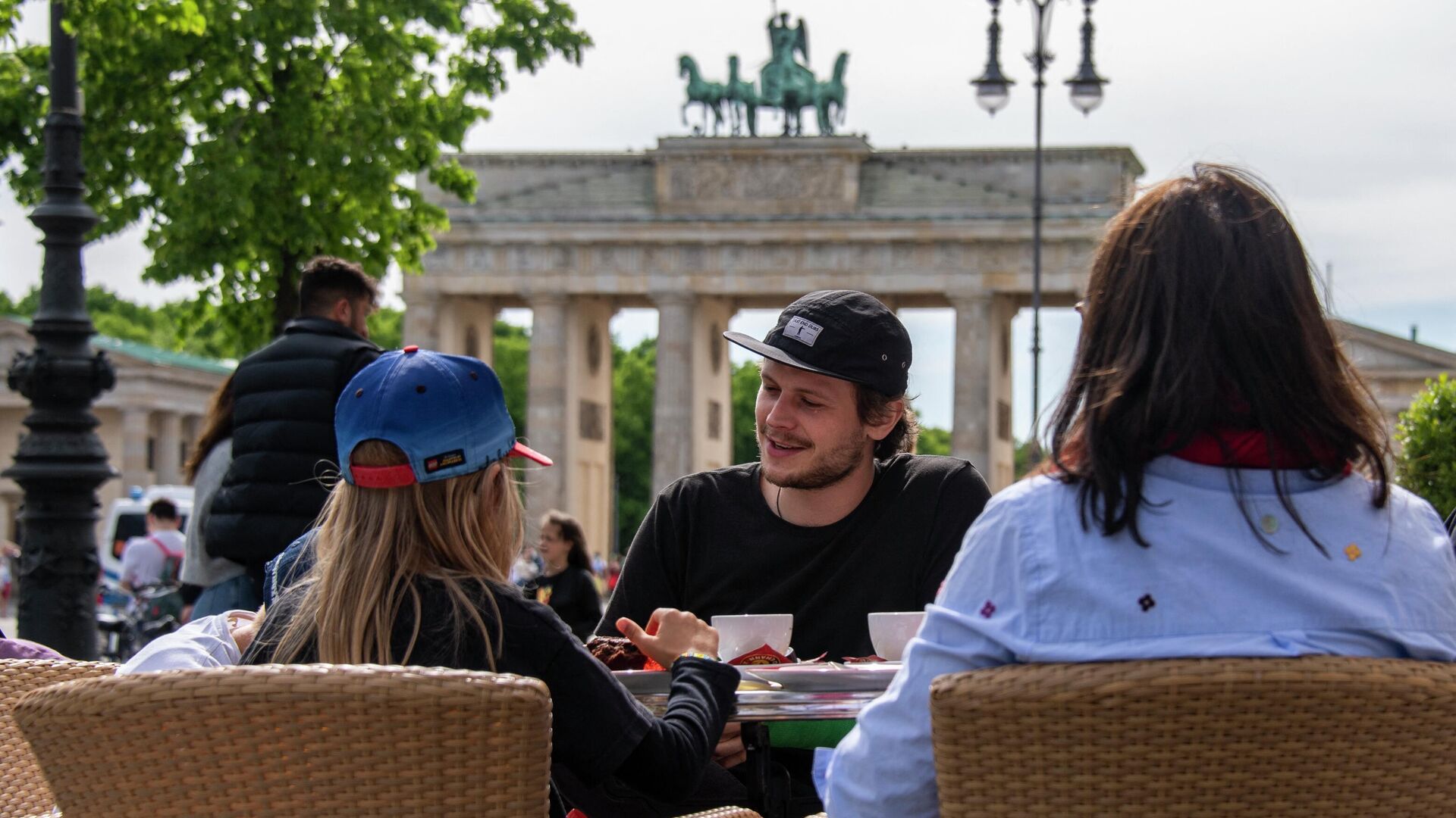 Люди сидят на террасе кафе возле знаменитых Бранденбургских ворот в Берлине  - Sputnik Moldova-România, 1920, 09.09.2022