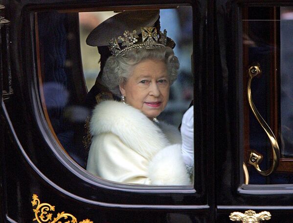 Королева Елизавета II приветствует толпу из своей конной повозки, когда она покидает Букингемский дворец на открытии парламента в Лондоне 6 декабря 2000 года. - Sputnik Молдова