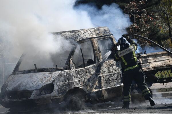 Сотрудник пожарной охраны ДНР тушит сгоревший автомобиль в результате обстрела центральной части города Донецка со стороны вооруженных сил Украины - Sputnik Молдова
