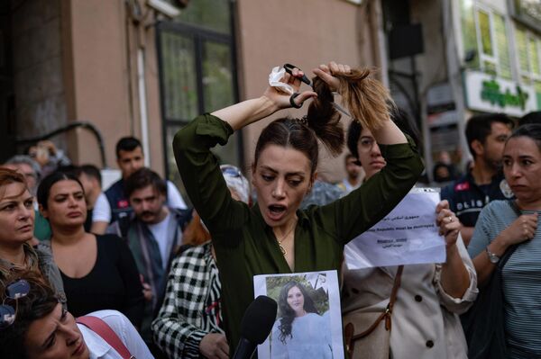 Насибе Самсаи, иранка, проживающая в Турции, отрезает себе волосы во время акции протеста у иранского консульства в Стамбуле 21 сентября 2022 года после смерти иранки после ее ареста полицией страны в Тегеране. - Sputnik Молдова