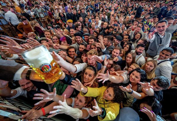 Молодые люди тянутся за бесплатным пивом в одной из пивных палаток в день открытия 187-го пивного фестиваля Октоберфест в Мюнхене, Германия, в субботу, 17 сентября 2022 года. - Sputnik Молдова