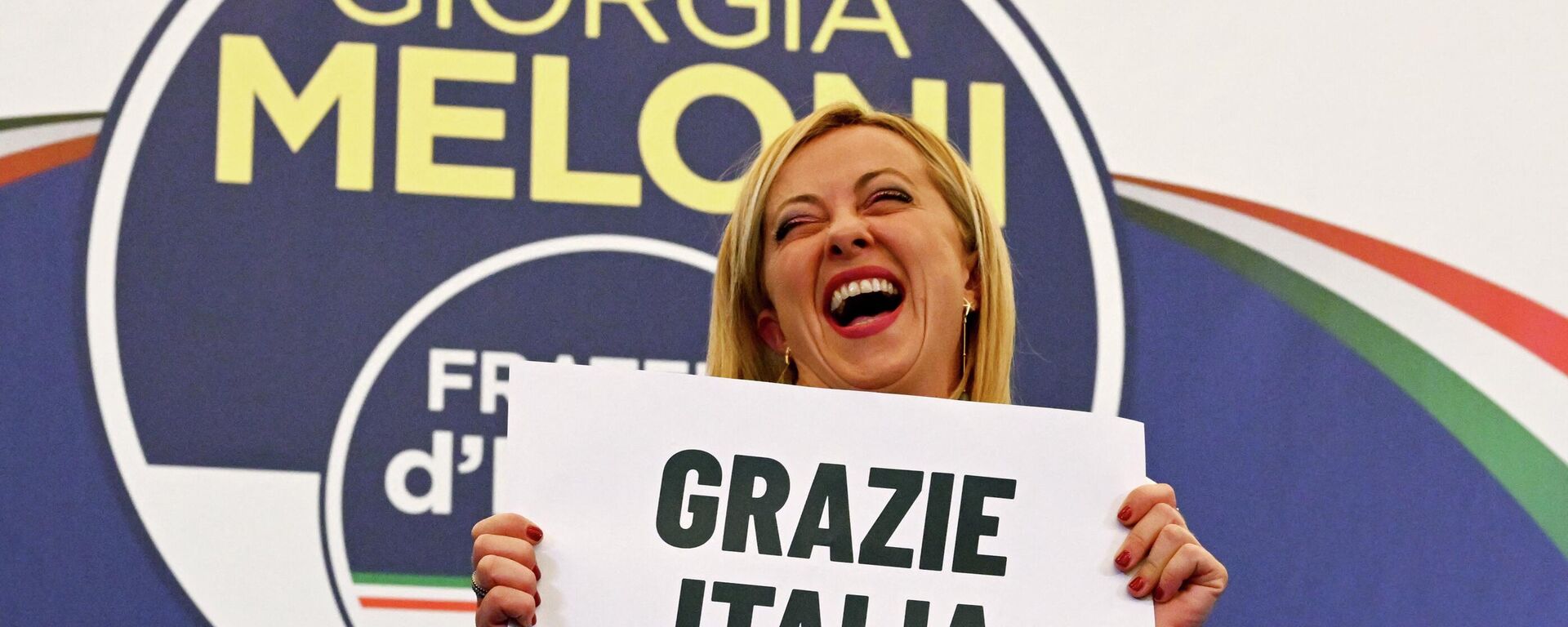 Лидер итальянской ультраправой партии Fratelli d'Italia Джорджа Мелони с плакатом с надписью Спасибо, Италия - Sputnik Молдова, 1920, 26.09.2022