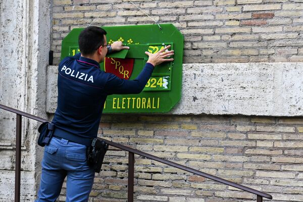 Un ofițer de poliție instalează placă oficială de identificare în fața unei secții de votare din Roma, în ajunul alegerilor legislative din țară. - Sputnik Moldova