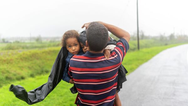 Мужчина несет двоих детей под дождем в поисках убежища после того, как ураган Иэн затопил их дом в Пинар-дель-Рио, Куба - Sputnik Moldova-România