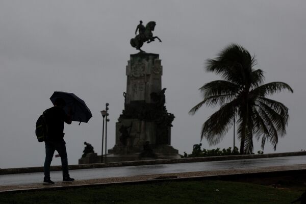 Un pieton folosește o umbrelă de ploaie în timpul trecerii uraganului Ian lângă Monumentul Antonio Maceo de-a lungul zidului Malecon din Havana, Cuba, joi dimineața, 27 septembrie 2022. (AP Photo/Ismael Francisco) - Sputnik Moldova-România