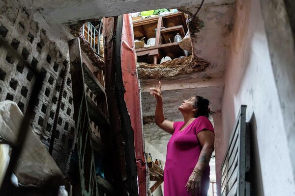 O femeie arată distrugerile din acoperișul casei sale, deasupra celui de-al doilea etaj, cauzate de uraganul Ian în Pinar del Rio, Cuba, marți, 27 septembrie 2022. Ian a atins pământul la 4:30 marți în provincia Pinar del Rio din Cuba, unde autoritățile au construit adăposturi, au evacuat oamenii, au luat măsuri urgente pentru a proteja culturile agricole din principala regiune de cultivare a tutunului. (AP Photo/Ramon Espinosa) - Sputnik Moldova-România