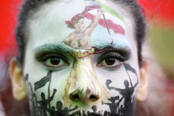 Девушка с раскрашенным лицом, изображающим Свободу, ведущую народ, на демонстрации в поддержку курдской женщины Махсы Амини во время акции протеста на площади Республики в Париже - Sputnik Молдова