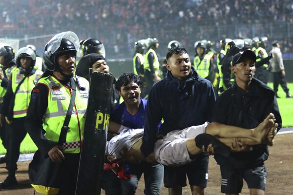 Футбольные болельщики несут раненого после столкновений во время футбольного матча на стадионе Канжурухан в Маланге, Восточная Ява, Индонезия - Sputnik Молдова