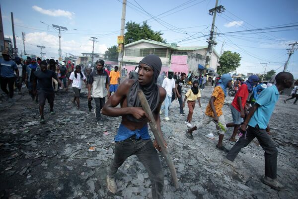 Протестующий несет кусок дерева, имитирующий оружие, во время акции протеста с требованием отставки премьер-министра Ариэля Генри в Гаити - Sputnik Молдова