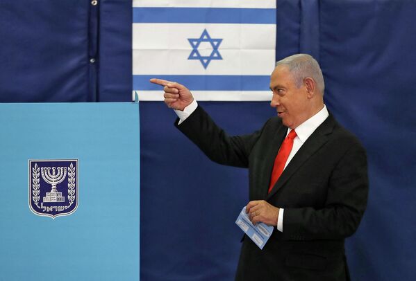 Premierul israelian Benjamin Netanyahu face un gest cu mâna în timp ce merge spre urna de vot într-o secție de votare din Ierusalim pe 23 martie 2021. - Sputnik Moldova-România