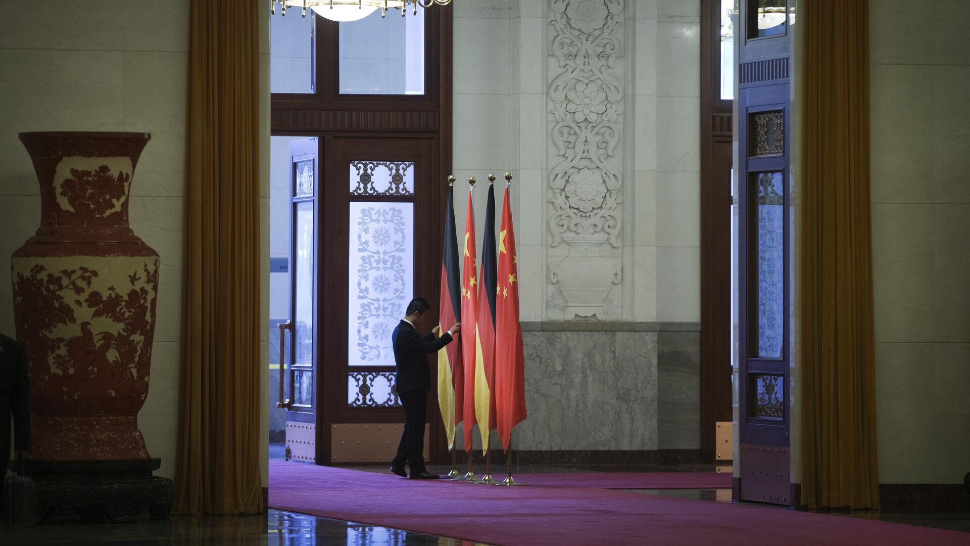 Работник поправляет флаги Германии и Китая в Доме народных собраний в Пекине - Sputnik Молдова, 1920, 19.11.2022