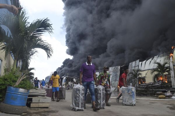Рабочие пытаются спасти багаж от пожара на фабрике и складе Yanuo в Асесе, штат Огун, на юго-западе Нигерии, 14 ноября 2022 г. (фото PIUS UTOMI EKPEI/AFP). - Sputnik Молдова
