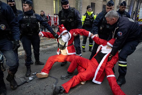 Французские полицейские эвакуируют активистов в костюмах Санта-Клауса в Париже, чтобы осудить политику правительства в области окружающей среды накануне начала саммита COP15 по биоразнообразию в Монреале  - Sputnik Молдова