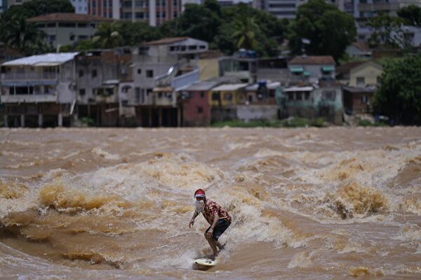 Surferul brazilian Paulo Guido surfează pe râul Doce în timp ce poartă o ținută de Crăciun în Governador Valadares, statul Minas Gerais, Brazilia - Sputnik Moldova