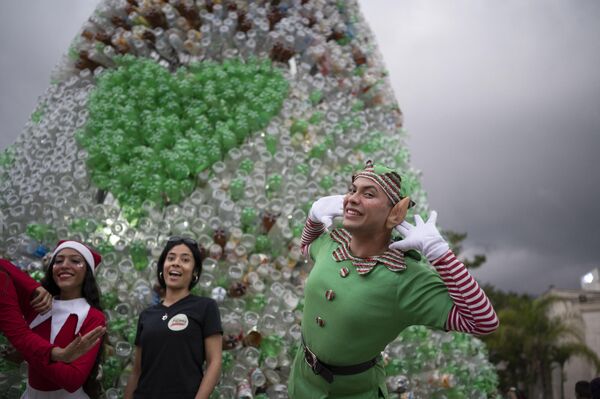 Tineri îmbrăcați în personaje de Crăciun pozează înaintea ceremoniei de aprindere a unui brad realizat din sticle de plastic reciclate de către organizația non-profit și non-guvernamentală Oko Spire, Caracas - Sputnik Moldova