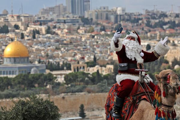 Палестинец в костюме Санта-Клауса на верблюде в Иерусалиме. - Sputnik Молдова