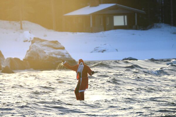 Человек в костюме Санта-Клауса во время серфинга в Финляндии. - Sputnik Молдова