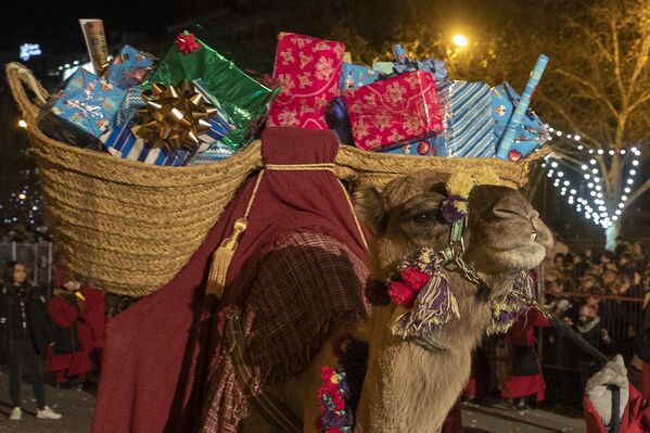 O cămilă purtând cadouri este condusă pe străzi în timpul paradei „Cabalgata de Reyes”, din Madrid, Spania, duminică, 5 ianuarie 2020. Parade colorate sărbătoresc Boboteaza, când creștinii observă vizita celor Trei Regi sau a celor Trei Înțelepți. (AP Photo/Paul White) - Sputnik Moldova-România