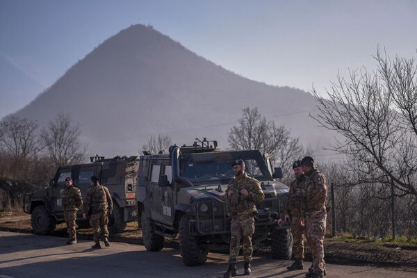 Soldați italieni aflați într-o misiune internațională de menținere a păcii condusă de NATO în Kosovo, patrulează lângă un drum baricadat cu camioane de sârbi în satul Rudare, lângă orașul Zvecan, pe 26 decembrie 2022. (Foto de Armend NIMANI / AFP) - Sputnik Moldova