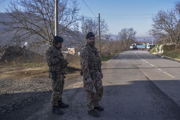 Soldați italieni aflați într-o misiune internațională de menținere a păcii condusă de NATO în Kosovo, patrulează lângă un drum baricadat cu camioane de sârbi în satul Rudare, lângă orașul Zvecan, pe 26 decembrie 2022. (Foto de Armend NIMANI / AFP) - Sputnik Moldova