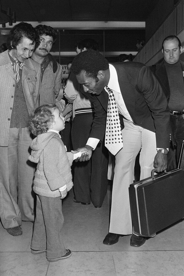 Fotbalistul brazilian Pele se scutură cu un copil, pe 12 septembrie 1976, când ajunge pe aeroportul din Orly, cu echipa sa New-York Cosmos, pentru a participa la un meci amical cu Paris Saint-Germain, pe 15 septembrie 1976. - Sputnik Moldova-România