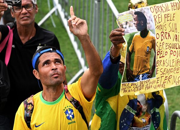 Un fan al regretatului fotbalist Pele schițează mai multe gesturi în timp ce asistă la ceremonia de adio pe stadionul Urbano Caldeira din Santos. - Sputnik Moldova-România