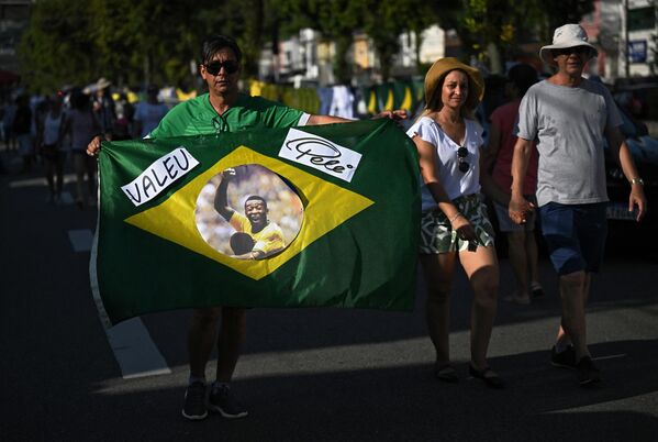 Скорбящий демонстрирует бразильский флаг с лицом легенды бразильского футбола Пеле возле стадиона Урбано Калдейра, также известного как Вила Бельмиро, где прошла церемония прощания, в Сантосе, штат Сан-Паулу, Бразилия, 2 января 2023 года. - Sputnik Молдова