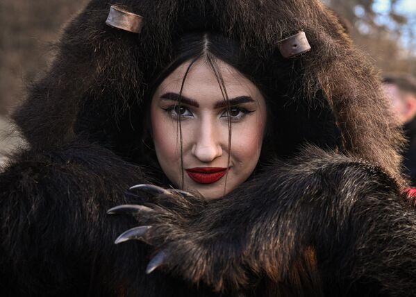 Девушка в костюме из медвежьей шкуры позирует во время парада медвежьей шкуры в Комэнешти, Румыния. - Sputnik Молдова