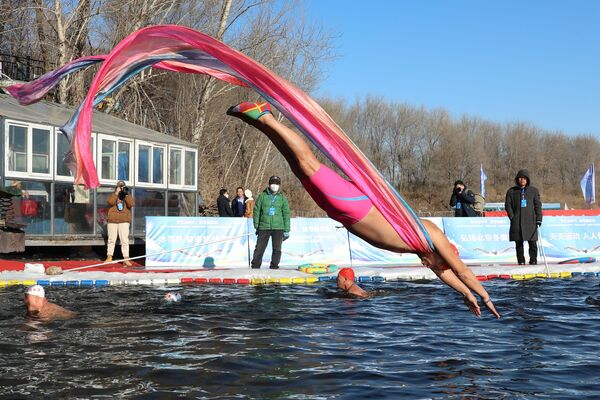 Любитель зимнего плавания ныряет в бассейн, вырезанный в замерзшем берегу реки, чтобы отпраздновать Новый год в Шэньяне, Китай. - Sputnik Молдова