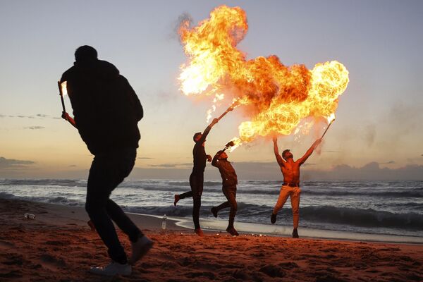 Палестинская молодежь демонстрирует свои навыки огнедышания на пляже в городе Газа, Палестина. - Sputnik Молдова