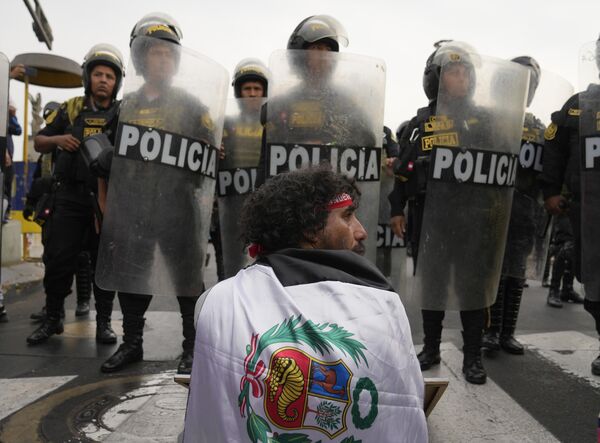 Мужчина сидит напротив шеренги полицейских во время марша против президента Перу Дины Болуарте в Лиме, Перу. - Sputnik Молдова