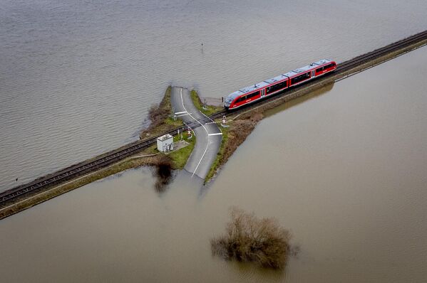 Поезд приближается к железнодорожному переезду между затопленными полями в Ниддерау-Айхен недалеко от Франкфурта, Германия. - Sputnik Молдова