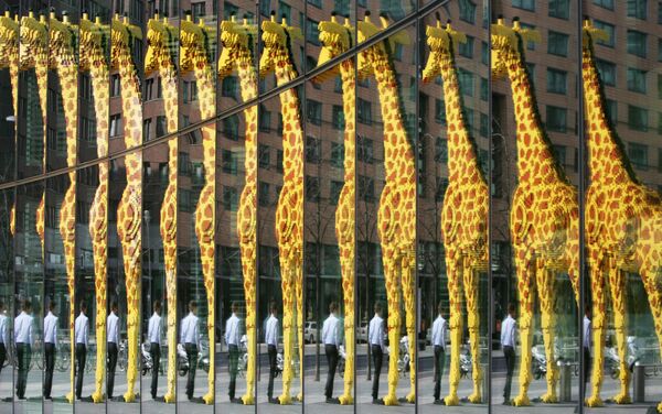 Гигантский жираф, сделанный из кубиков Lego, отражается в стеклянном фасаде в Берлине. - Sputnik Молдова