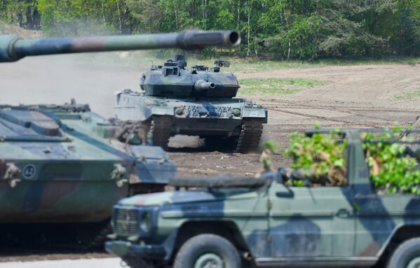 Această fotografie a fost făcută pe 20 mai 2019 și arată un tanc de luptă Leopard 2 A7 (în fundal) al forțelor armate germane participând la exercițiile „Forța operațională comună de pregătire foarte înaltă”, ca parte a unității de tancuri din zona de pregătire militară NATO din Munster, nordul Germaniei. - Sputnik Moldova