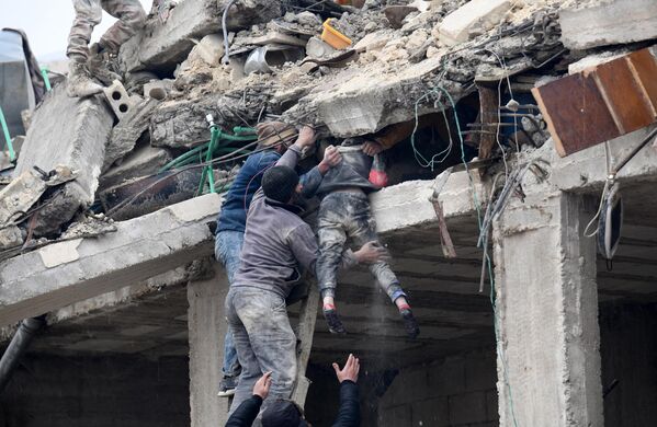 Locuitorii ajută o fată rănită să iasă de sub dărâmăturile unei clădiri prăbușite în urma cutremurelor. Imaginea a fost surprinsă în orașul Jandaris, Siria - Sputnik Moldova