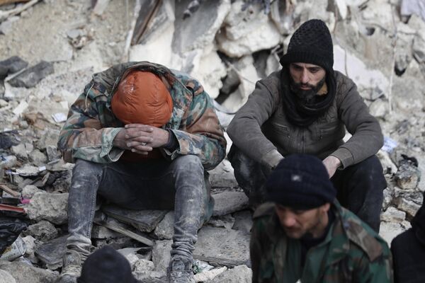 Supravețuitorii cutremurului care a devastat Turcia și Siria stau pe o placă de beton a unei clădiri prăbușite. Imaginea a fost surprinsă în localitatea Alep, Siria - Sputnik Moldova